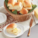 A basket of King's Hawaiian dinner rolls with butter on a plate.