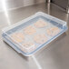 A plastic container with a Vollrath sheet pan of cookies on a counter.
