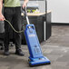 A person using a Clarke CarpetMaster 215 vacuum cleaner in a corporate office cafeteria.