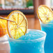 Two blue drinks garnished with dried navel orange slices.