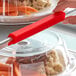 A person using a Baker's Mark red silicone sheet pan clip to serve food.