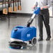A woman using a Clarke Vantage cordless walk behind floor scrubber to clean a floor.
