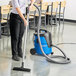 A woman using a Nilfisk wet/dry vacuum to clean a floor.