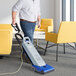A man using a Clarke CarpetMaster 112 vacuum cleaner to clean a carpet in a corporate office cafeteria.