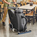 A man using a Clarke Summit Pro wet/dry vacuum to clean a floor in a room with a white table and black chairs.