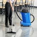 A woman using a Clarke Maxxi II wet/dry vacuum to clean a floor.