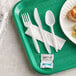A green tray with a white plastic fork, spoon, and knife.