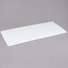 A white rectangular Winholt Sani-Platter on a gray surface.