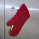 A red San Jamar oven mitt hanging on a refrigerator door.