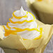 A cupcake with Satin Ice Yellow Vanilla Glitter Glaze yellow swirls on top.