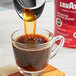 A glass cup of Lavazza Premium House Blend coffee being poured