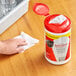 A hand using Sani Professional sanitizing wipes to clean a table in a professional kitchen.
