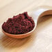 A wooden spoon filled with blackberry powder.