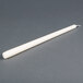 A 12 inch ivory Will & Baumer taper candle on a gray surface.