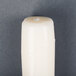 A white Will & Baumer taper candle on a gray surface.