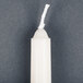 A white candle in a white cylinder with a long thin wick.