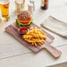 An Acopa walnut faux wood melamine serving board with a burger and fries on it.