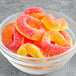 A bowl of Kervan Gummy Peach Rings on a gray surface.