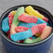 A bowl of Kervan neon sour gummy worms on a table.