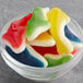 A bowl of Kervan assorted colored gummy sharks on a table.