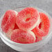 A close-up of a bowl of Kervan Gummy Strawberry Rings with red and white candies.