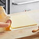 A person rolling out Anchor Food Professionals unsalted butter on a wooden table.