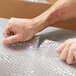 A person's hand cutting a piece of Pregis small perforated bubble wrap.