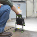 A person using a PowerSmith black and green work light with a power tool.