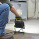 A person using a black and green PowerSmith LED work light to clean a floor.