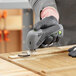 A person using a Genesis cordless oscillating tool to cut wood.