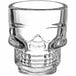 A clear glass Acopa skull shot glass with a skull design.
