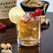 A Libbey double old fashioned glass of whiskey on ice with a cherry and a lemon slice.