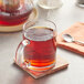 A glass mug of Davidson's Organic Ceylon Orange Pekoe Black tea on a coaster with a spoon