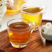 A glass cup of Davidson's Organic Energize Loose Leaf Tea with a bowl of sugar cubes.
