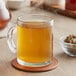 A glass mug of brown Davidson's Organic Ginger Spice herbal tea with steam rising from it.