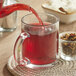 Davidson's Organic Cranberry Orange Herbal Tea being poured into a glass.