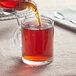 A teapot pouring Davidson's Organic Earl Grey tea into a glass cup.