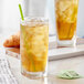 A glass of Davidson's Organic Tulsi Pure Leaves Herbal Iced Tea with a straw.