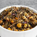 A bowl of Davidson's Organic Green Tea Garden loose leaf tea with dried herbs.