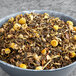 A bowl of Davidson's Organic Tropical Green loose leaf tea with dried flowers.