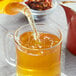 A person pours Davidson's Organic Orange Spice Herbal tea into a glass.