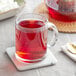 A glass mug of Davidson's Organic Berry Essence Herbal Loose Leaf Tea on a white marble coaster.