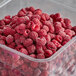 A plastic container filled with IQF Organic Red Raspberries.