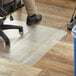 A person sitting in a chair on a clear office chair mat.