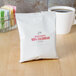 A white bag with red text for Ellis 100% Colombian Decaf Coffee next to a cup of coffee.