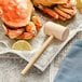 A pair of crabs with a Choice Wooden Lobster Mallet and lemon on newspaper.