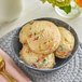 A bowl of Cookie Dough Bliss vegan cake batter cookie dough on a table with three scoops of ice cream and sprinkles.