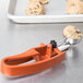 A Vollrath red ice cream scoop with cookie dough in it.