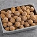 A metal tray with brown Gardein plant-based meatballs on it.