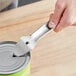 A hand using a Choice nickel-plated steel bottle or can punch opener to open a can.